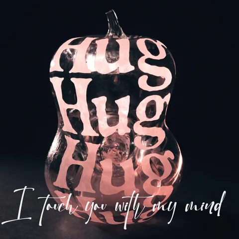 کاور آلبوم: کدوی شیشهای صورتی و روشن که کلمهی Hug چند بار روش نوشته شده، با جملهی دستنویس I touch you with my mind.